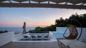Une terrasse extérieure avec vue sur la mer, un jacuzzi et des chaises longues.