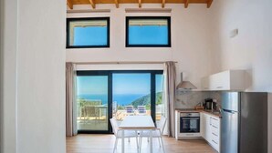 Une cuisine moderne dotée d’une grande fenêtre, d’un coin repas et offrant une vue sur la mer.