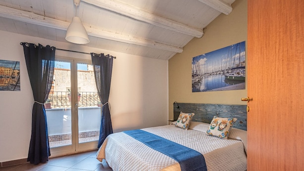 Un dormitorio con cama, cortinas, un cuadro y vistas por la ventana.
