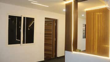 A modern hallway with a large mirror, recessed lighting, and a door with a number sign.