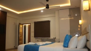 A modern bedroom with a large bed, a ceiling fan, and a wardrobe. - Niharika Heights Luxury Hotel (Bengaluru)