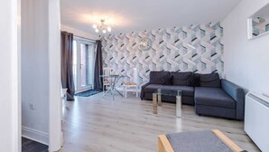 En moderne stue med en grå sofa, et glasbord og en væg med mønster.