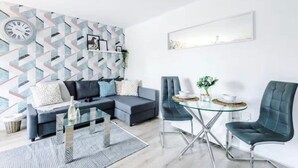 En moderne stue med en hjørnesofa, et sofabord i glas og to lænestole.