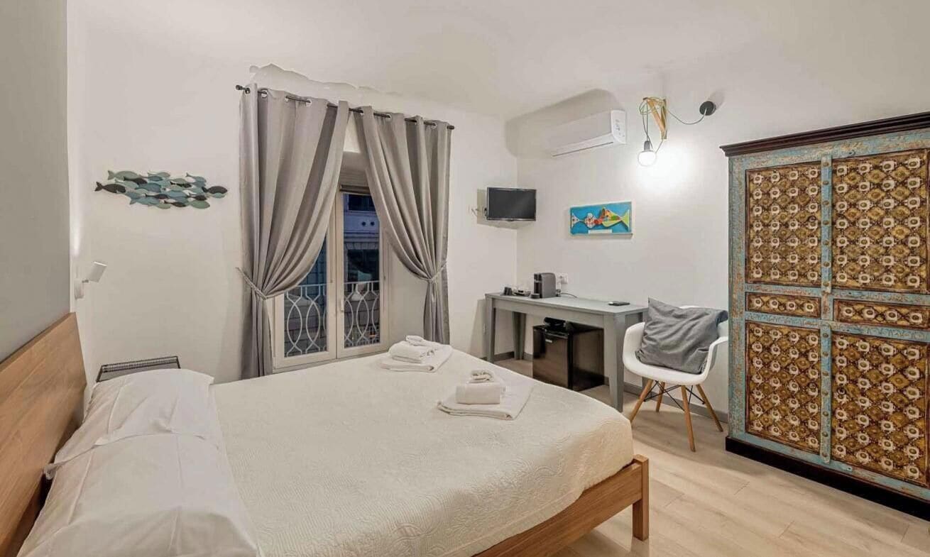 A bedroom with a bed, a desk, a chair, a TV, and a wardrobe.