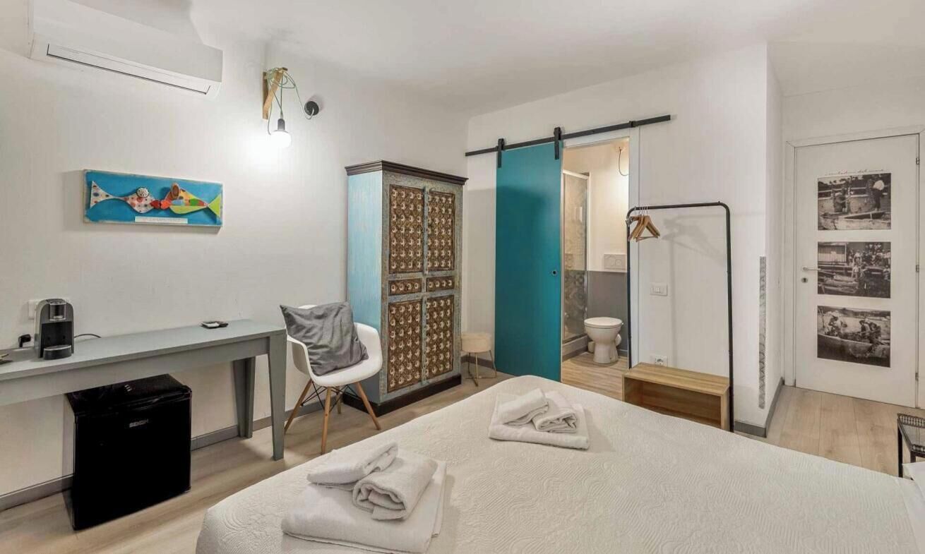 Habitación de hotel con cama, escritorio, silla, armario, baño y puerta decorada con imágenes.