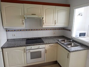 A kitchen with white cabinets, a built-in oven, a microwave, and a granite countertop. - Triplex del Duque (Fañabe)
