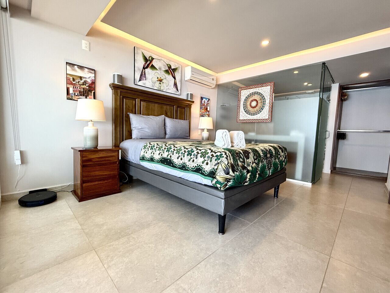 Une chambre moderne avec un lit, des tables de chevet et un climatiseur fixé au mur.
