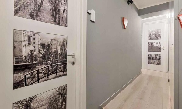 A hallway with a light gray wall, a door with a heart-shaped decoration, and a staircase leading to another room. - Welcome to I Profumi del Mare, our guesthouse in the heart of La Spezia.We offer three spacious and tastefully furnished rooms, each with a private bathroom. Each room is an oasis of tranquility, and well designed to guarantee maximum comfort.The guestho (La Spezia)
