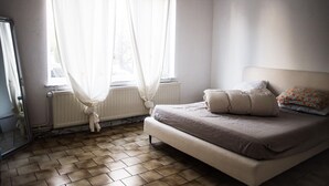 Un dormitorio con cama, un radiador y una ventana con cortinas.