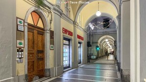 Un couloir bordé de boutiques des deux côtés, notamment une boutique Emporio et une boutique Nuova.