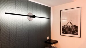 Une chambre moderne avec un mur orné d’un motif géométrique, un tableau encadré accroché au mur et une table de chevet.