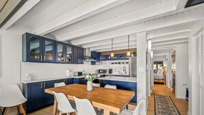 Una cucina moderna con tavolo e sedie in legno, un'isola integrata e vista sull'area soggiorno adiacente.