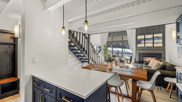 Una cucina moderna con isola centrale, tavolo da pranzo in legno e una scala che conduce a un piano superiore.