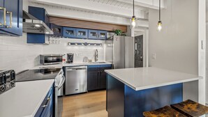 Una cucina moderna con elettrodomestici in acciaio inossidabile, mobili blu e un'isola centrale.