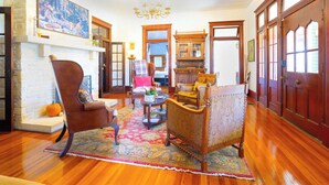 A spacious living room with hardwood floors, a large rug, and classic furniture including a leather armchair and a patterned sofa. - 1906 Estate For 21 Guests W/pool,hot Tub (Comfort)