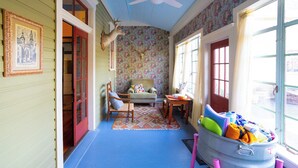 A room with a blue floor, a wooden chair, a sofa, a table, a suitcase, and a deer head mounted on the wall. - 1906 Estate For 21 Guests W/pool,hot Tub (Comfort)