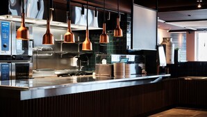 Una cucina moderna con elettrodomestici in acciaio inossidabile, lampade a sospensione in rame e un piano di lavoro in legno.