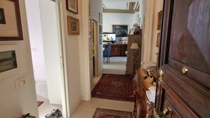 Un couloir avec une porte en bois, un tapis et des tableaux encadrés accrochés aux murs.