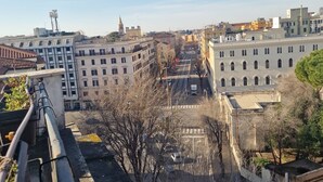 Une vue urbaine mettant en valeur un bâtiment imposant, doté d’une grande entrée en arc de cercle et d’une tour horloge.
