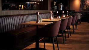 Un restaurante con asientos de cuero y mesas de madera, equipado con lámparas de cobre y una máquina de café.