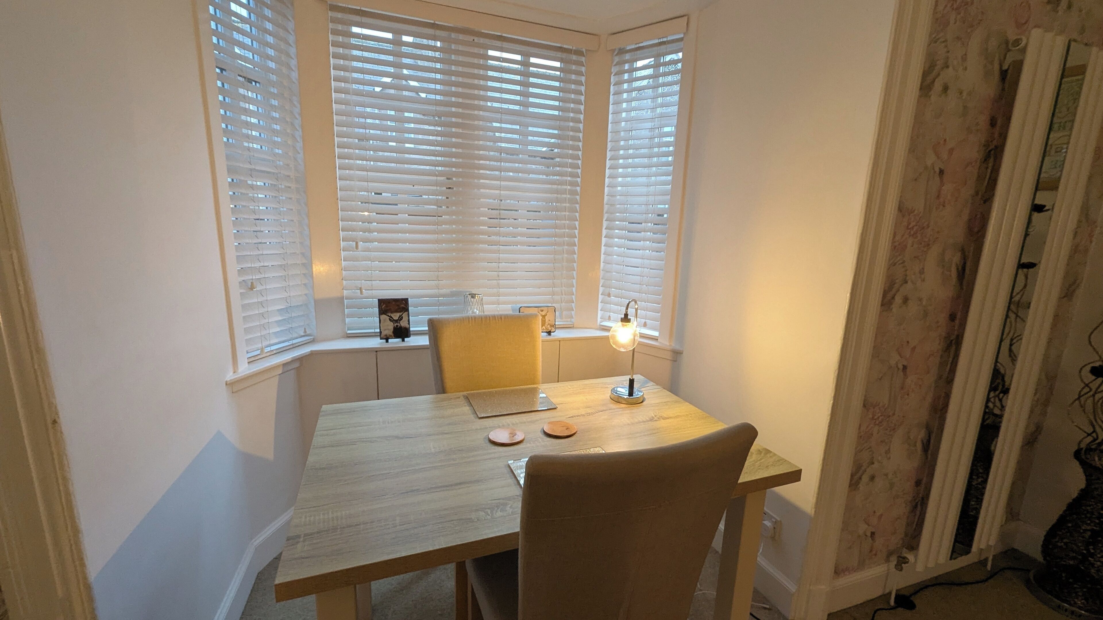 Un comedor con una mesa de madera, dos sillas y una lámpara de mesa.