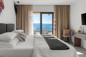 A modern hotel room with a large bed, a desk, and a view of the sea. - NEW! Stylish Villa Collina - Stunning Sea Views, Private Pool, Top amenities (Duće)