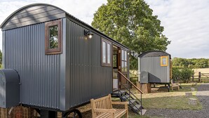 En liten, envåningsbyggnad av metall med en veranda och en träbänk.
