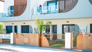 A modern two-story building with a gated entrance, a sign for 'Snow House' with a sales phone number, and a small garden area with plants and a bench. - Benoa Zen Ground-floor luxury, direct pool access, by Oyoostays (Pilar de la Horadada)