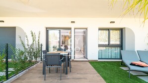 A modern outdoor patio with a dining table and chairs, a grassy area, and a seating area with cushions. - Benoa Zen Ground-floor luxury, direct pool access, by Oyoostays (Pilar de la Horadada)