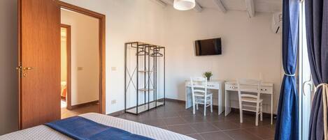 Ein Schlafzimmer mit einem Bett, einem Schreibtisch, zwei Stühlen, einem Fernseher und einem Kleiderschrank.