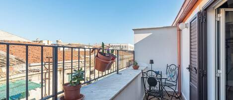 Parvekkeella on ruukuissa olevia kasveja, pöytä ja tuoleja.