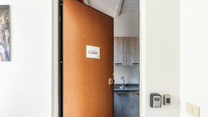 Puinen ovi, jossa on kyltti, jossa lukee ”Cala”, johtaa keittiötilaan, jossa on kaappeja ja pesuallas.