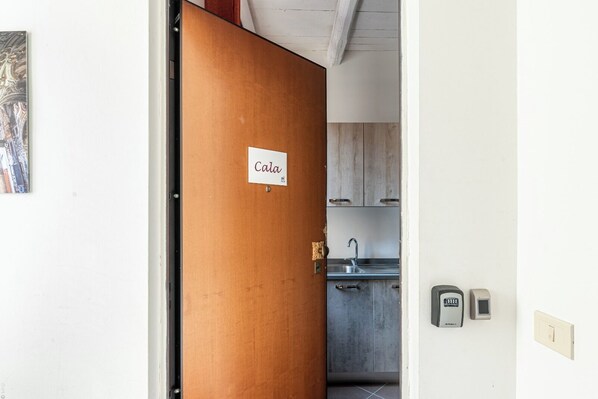 A wooden door with a sign reading "Cala" leading to a kitchen area with cabinets and a sink. - Casa Peppa by Wonderful Italy (Palermo)