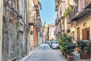 A narrow street lined with multi-story buildings, some with balconies and outdoor seating. - Casa Peppa by Wonderful Italy (Palermo)