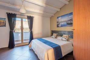 Een slaapkamer met een bed, gordijnen, een schilderij en een balkon.