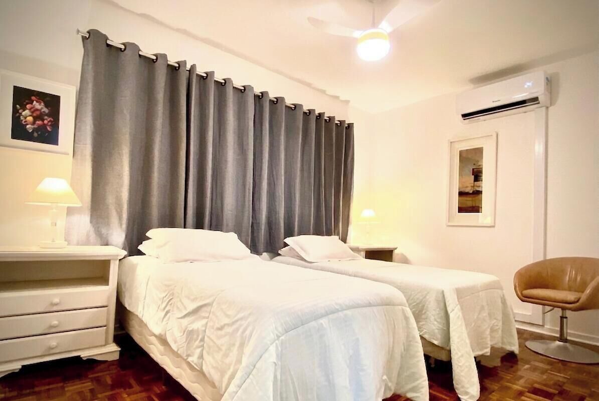 Ein Hotelzimmer mit zwei Betten, einem Sessel, einem Deckenventilator und einer Klimaanlage.