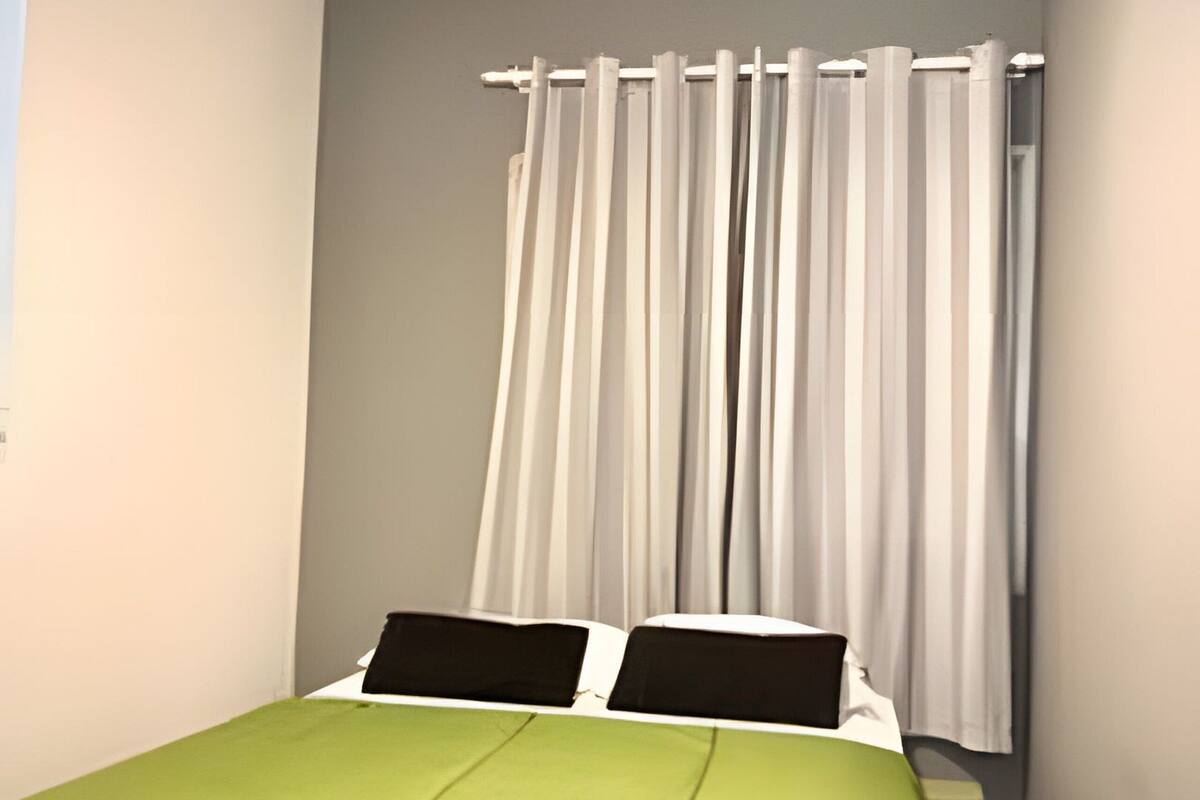 A bedroom with a bed, a ceiling fan, and a window with curtains.