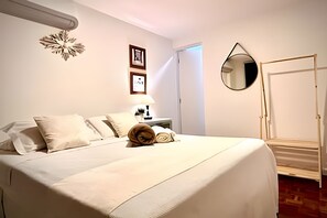 A hotel room with a bed, a bedside table with a lamp, a mirror, and a door. - Residencial Vila Olimpia (São Paulo)