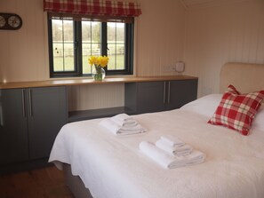 A bedroom with a bed, pillows, a window with a view, and a vase with flowers. - The Lodge (Bromsgrove)