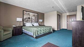 Une chambre d’hôtel avec un lit, un bureau, une chaise, un grand tableau au mur et une armoire en bois.