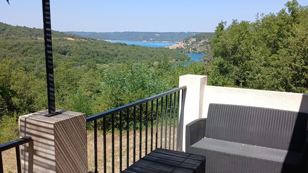 A balcony with a view of a lake, a wicker sofa, and a tiled floor. - Detached house 90m south facing for 6 people with air conditioning (Bauduen)