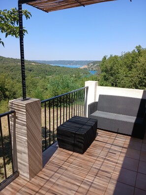 A balcony with a view of a lake, a wicker sofa, and a tiled floor. - Detached house 90m south facing for 6 people with air conditioning (Bauduen)