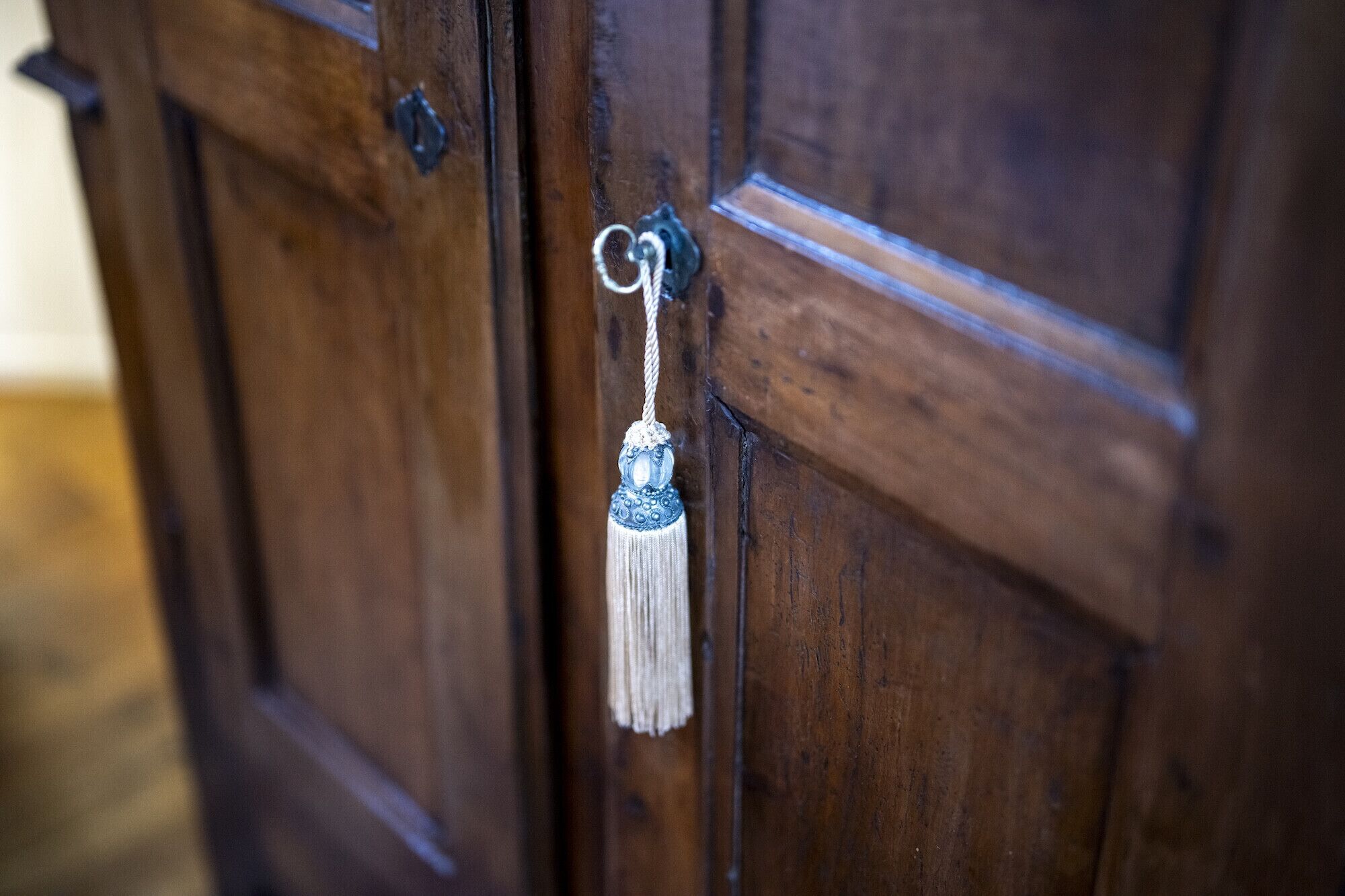 A wooden door with a metal keyhole and a decorative keychain.