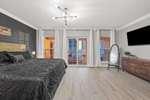 Ein modernes Schlafzimmer mit einem großen Bett, einer Deckenleuchte, einem Schminktisch, einem Spiegel und einem Fernseher.