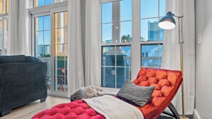A modern living room with a red tufted sofa, a black armchair, and a floor lamp. - Pirate's Pearl | Pool | Balcony | Steps to Beach (Panama City Beach)