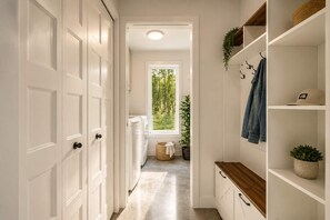 A hallway with white doors, a laundry area, and a view of greenery outside. - Spa | Relaxation Net | Le Dormëa (Saint-Côme)