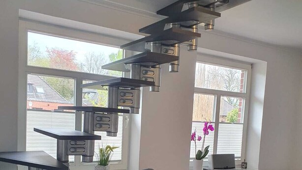 Ein modernes Wohnzimmer mit einem grauen Sessel, einem kleinen Tisch und einer außergewöhnlichen Deckenleuchte.