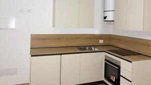 A modern kitchen with white cabinets, a wooden countertop, a stainless steel sink, and a built-in oven.