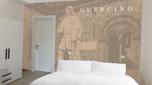A bedroom with a bed, wardrobe, and a wall with a mural.