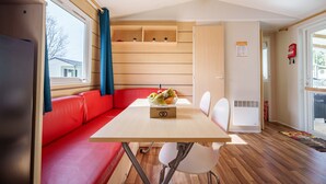 A compact room with a wooden table, a red sofa, and a window with curtains.